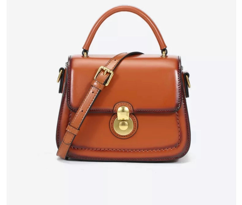 Small genuine leather handbag with gold fixtures, a handle and a removable shoulder strap